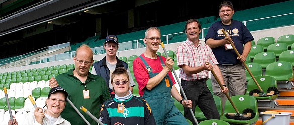 Mitarbeiter und Mitarbeiterinnen des Martinshofes mit Reinigungsutensilien im Weser-Stadion